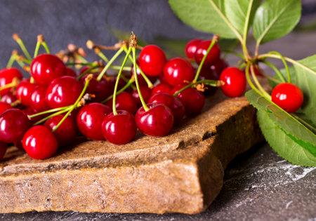 Fresh sour cherries and green leaves on the board. Fresh ripe sour cherries.の写真素材