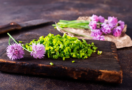 Purple onion flower and fresh green onion on board