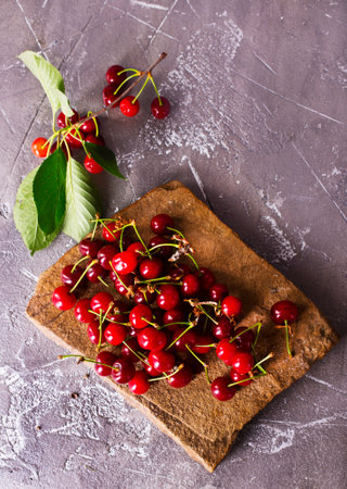 Fresh sour cherries and green leaves on the board. Fresh ripe sour cherries.の写真素材