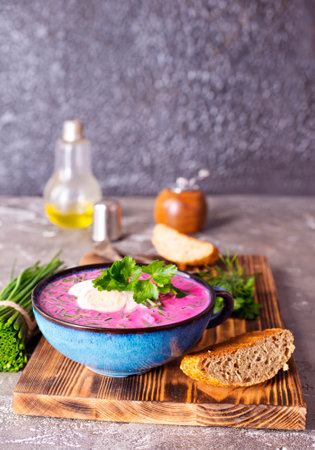 Traditional east european soup. Cold summer soup of beets, kefir, cucumbers, eggs and dill in a blue bowl closeup. Summer food, Eastern European cuisine.の写真素材