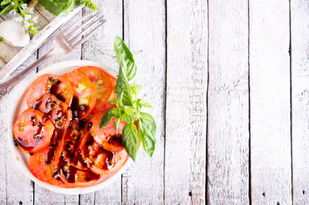 Healthy tomato Salad with tomato, topping balsamic sauce and basil on white plate. Fresh salad bowlの写真素材