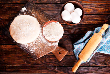 Fresh dough on board with flour, ingredients for bakingの写真素材