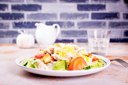 Caesar salad with chicken lettuce bread potatoes on round plate on light backgroundの写真素材