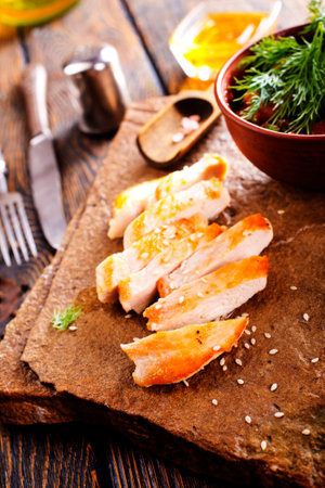 Grilled chicken breast with spice rub and lemon on a cutting boardの写真素材
