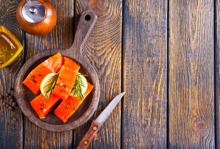 Fresh salmon fillets on dark wooden background with herbs and spices.の写真素材