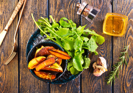 Baked potato wedges with addition sea salt and rucola on wooden background, top viewの写真素材