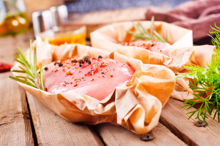 Fresh chicken breast fillet on a wooden table with spices and fresh greensの写真素材