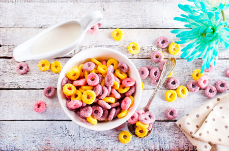 Falling colorful corn rings in bowl on white tableの写真素材