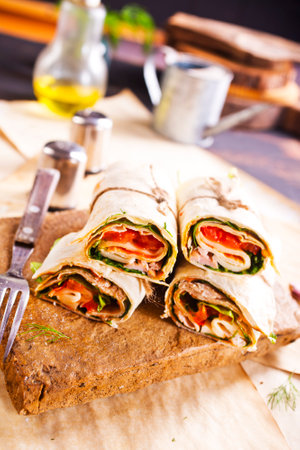 Sliced sandwich tortilla with tomatoes, salad, cream cheese and ham. Wrap rollsの写真素材