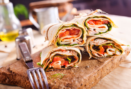 Sliced sandwich tortilla with tomatoes, salad, cream cheese and ham. Wrap rollsの写真素材