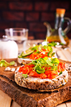 Fresh whole wheat sandwiches with smoked salmon on a wooden tableの写真素材