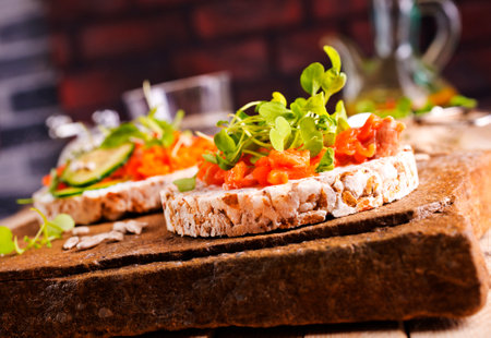 Fresh whole wheat sandwiches with smoked salmon on a wooden tableの写真素材
