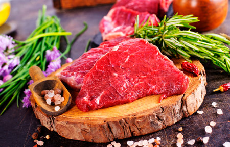 Board with fresh raw steak meat on wooden tableの写真素材