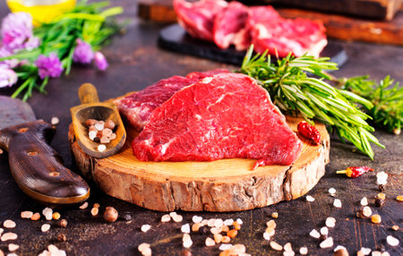 Board with fresh raw steak meat on wooden tableの写真素材