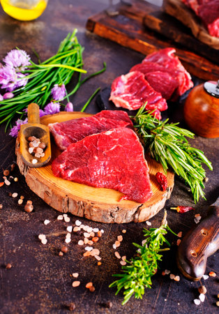 Board with fresh raw steak meat on wooden tableの写真素材