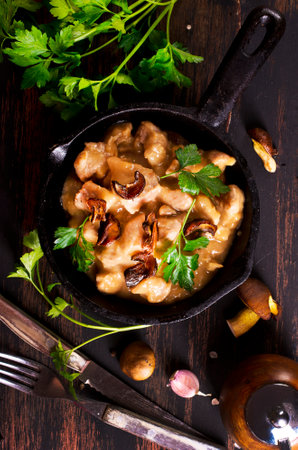 meat with mushroom sauce in pan on a tableの写真素材