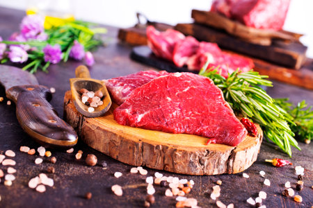 Board with fresh raw steak meat on wooden tableの写真素材
