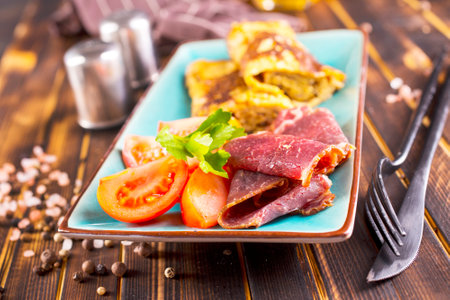 omelet with smoked meat, tomato and spice on plateの写真素材