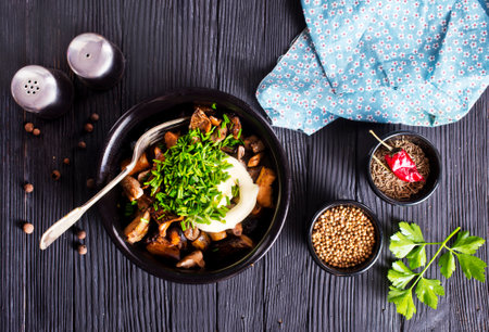 fried mushrooms with onion and sour cream in black bowlの写真素材