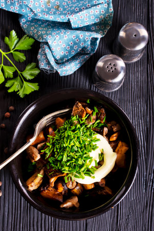 fried mushrooms with onion and sour cream in black bowlの写真素材