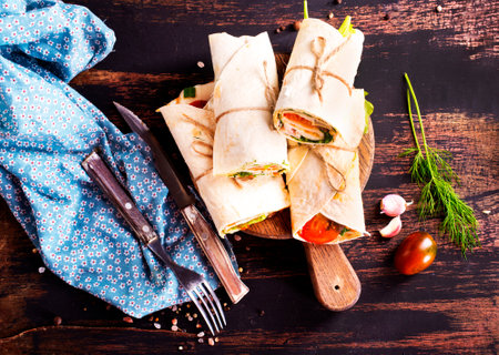 Ham roll with cheese and vegetables on paperの写真素材