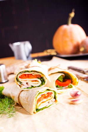 Ham roll with cheese and vegetables on paperの写真素材