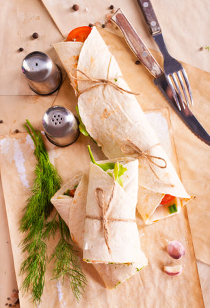 Ham roll with cheese and vegetables on paperの写真素材
