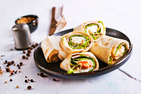 roll with bacon and cheese on the black plate on a tableの写真素材