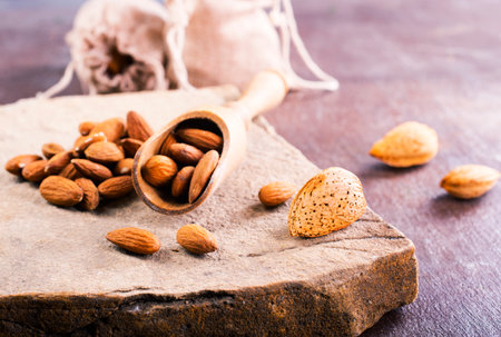 Fragrant roasted almonds with kitchen utensils on a stone table, close-up, top view.の写真素材