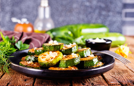 Tasty fried zucchini slices on a plate with sauce on a wooden table.の写真素材