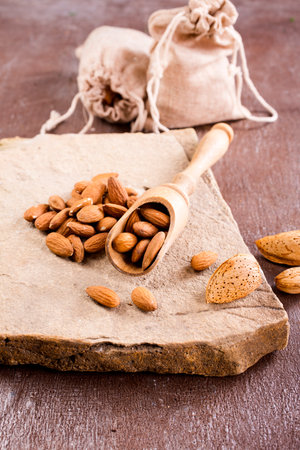 Fragrant almonds with kitchen utensils on a stone table, close-up, top view.の写真素材