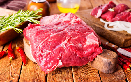 Raw meat on cutting board, with herbs, spices on cooking tableの写真素材