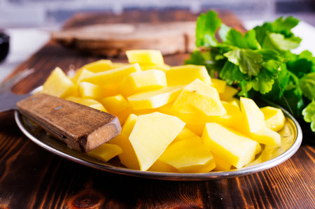 Spiced pieces of raw potato prepared to bake on metal plateの写真素材