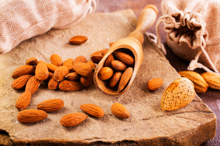 Fragrant roasted almonds with kitchen utensils on a stone table, close-up, top view.の写真素材