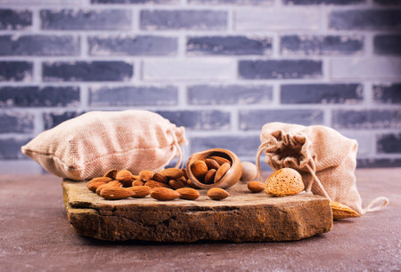 Fragrant roasted almonds with kitchen utensils on a stone table, close-up, top view.の写真素材