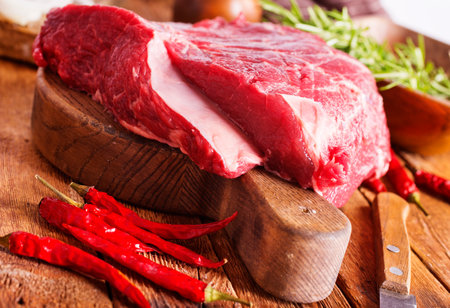 Raw meat on cutting board, with herbs, spices on cooking tableの写真素材