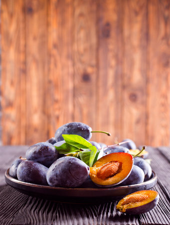Ripe plum on dark wooden background in rustic styleの写真素材