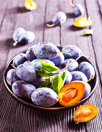 Ripe plum on dark wooden background in rustic styleの写真素材