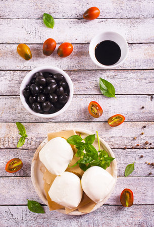 Traditional italian food - white ball mozzarella Italian soft cheese with cheese knife, tomato, basil, olivesの写真素材