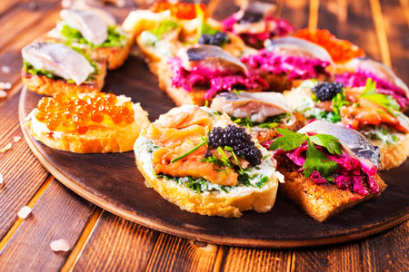 Bread with fish, salami and cheese. Sharing antipasti on party or summer picnic time over wooden...