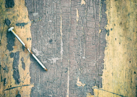 Rusty nail on a background of old table. Retro toned photoの写真素材