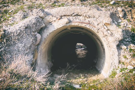 Old sewage pipe and the stream running through it in the arid terrainの写真素材