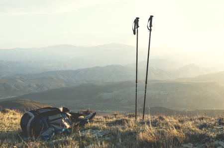 Ascent into the mountains, nordic walking sticks and a backpack, a traveler's set. Wonderful sunset in the backgroundの写真素材
