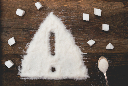 Sign of warning attention made of granulated sugar. A conceptual photo illustrating the harm from consuming white refined sugar and products containing itの写真素材
