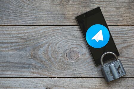 MOSCOW, RUSSIA, April 17, 2018. Icon of the popular messenger Telegram on the smartphone screen with a lock and a key on a wooden background. Blocking Telegram service by Roskomnadzor in Russiaのeditorial素材