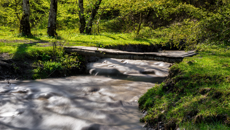Wooden bridge over a small ravine in the forest. Shot with long exposureの写真素材