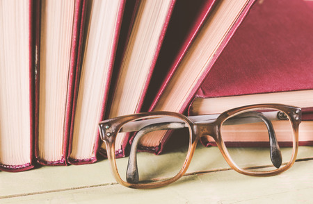 Old glasses with a pile of books, photo with a vintage effectの写真素材
