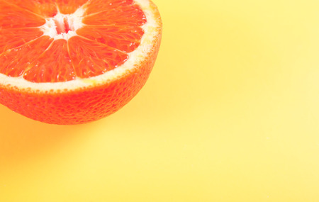 Top view of a half bloody orange fruit on yellow pastel colored backgroundの写真素材