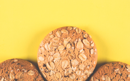 Oatmeal cookies with a sprinkling of oat flakes and seeds on a yellow backgroundの写真素材