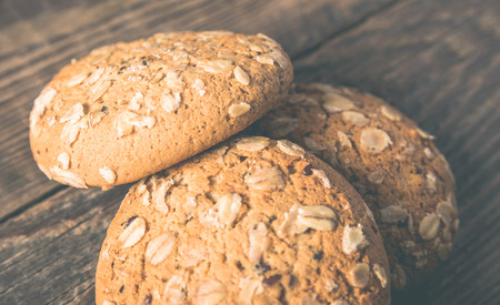 Oatmeal cookies with a sprinkling of oat flakes and seeds on a wooden backgroundの写真素材
